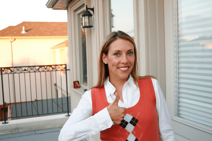 drone roof inspection. Happy homeowner. Woman standing on her porch giving a thumbs up.