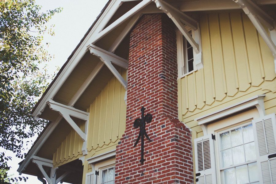 How to get your roof ready for winter. Looking up at a yellow house with a red brick chimney and a overhanging roof.