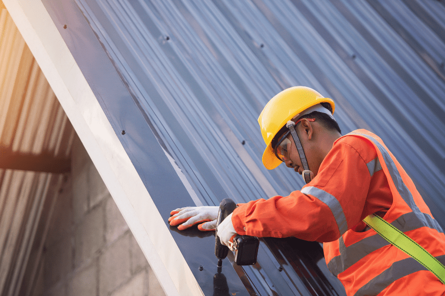 Maintenance for Metal Roofs showing a trained roofer attaching flashing to a metal roof.